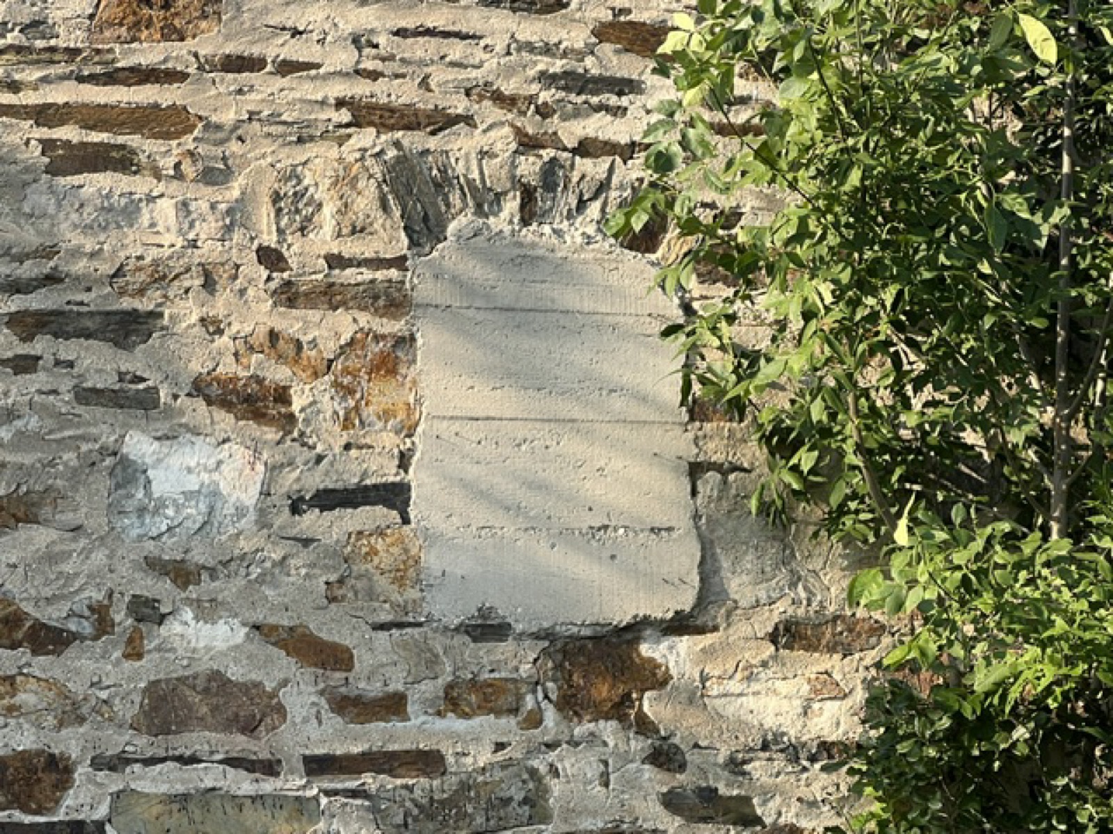 Arched opening in the stone wall filled with formed concrete
