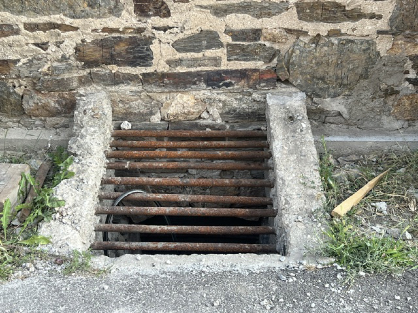 A window well cut into the stone with rusted iron bars